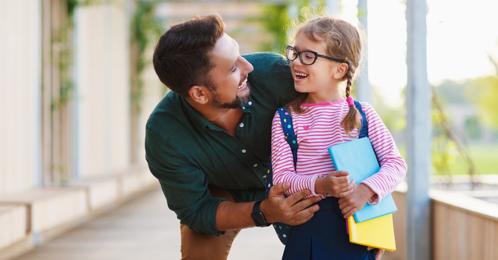 first day at school. father leads little child school girl in first grade.